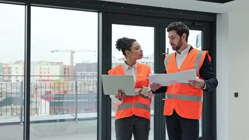 Arquitecto e ingeniero discuten los planos de un edificio en construcción
