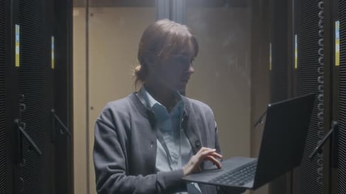 Woman Working on Laptop in Server Room