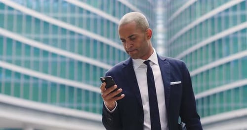 An business man in a suit and tie is happy and smiling while sending messages, working emails or c