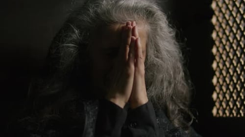 Elderly Female Churchgoer Praying inside Confessional Booth