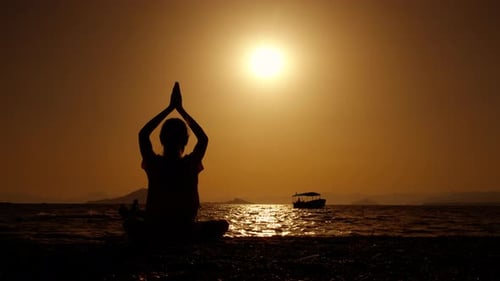 Silhouette Meditating on Beach at Sunrise