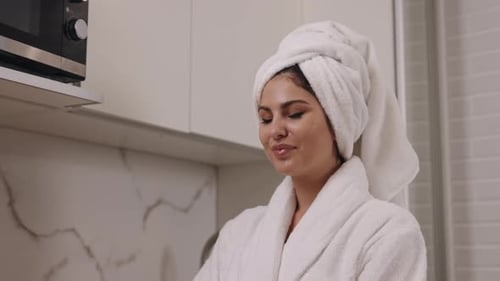 Woman in Robe Tosses Apple in Kitchen