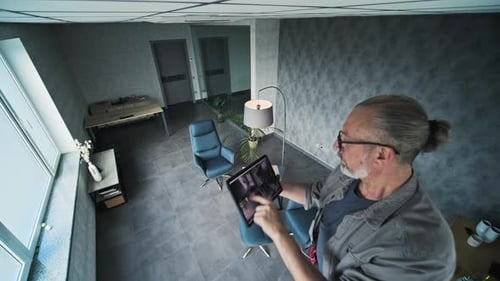 Man Uses Tablet for Security Monitoring in Office