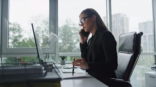 Confident businesswoman talking business on phone working remotely in office