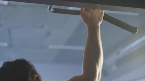 Nahaufnahme eines athletischen, muskulösen Mannes, der Klimmzüge an einer horizontalen Stange macht