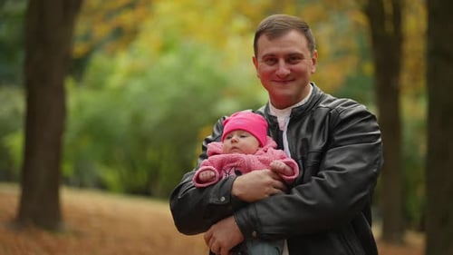 Loving Father Holding Baby Daughter in Autumn Park