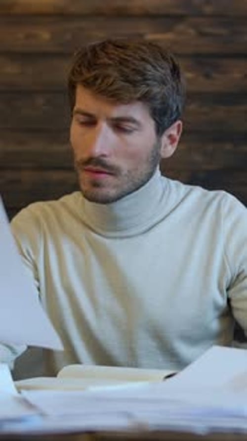 Handsome Man Reviews Paperwork at Desk Indoors