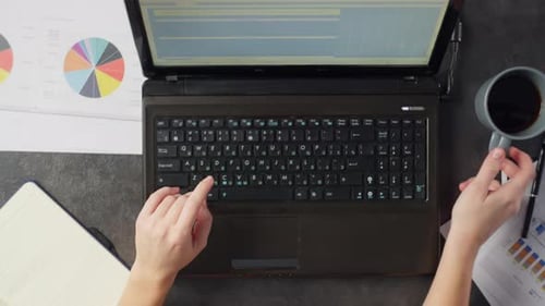 The Woman is Typing on the Computer and Drinking a Cup of Coffee