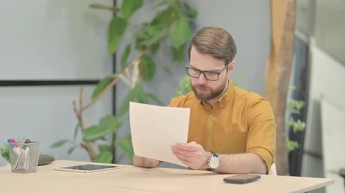 Young Man Reading Documents in Office