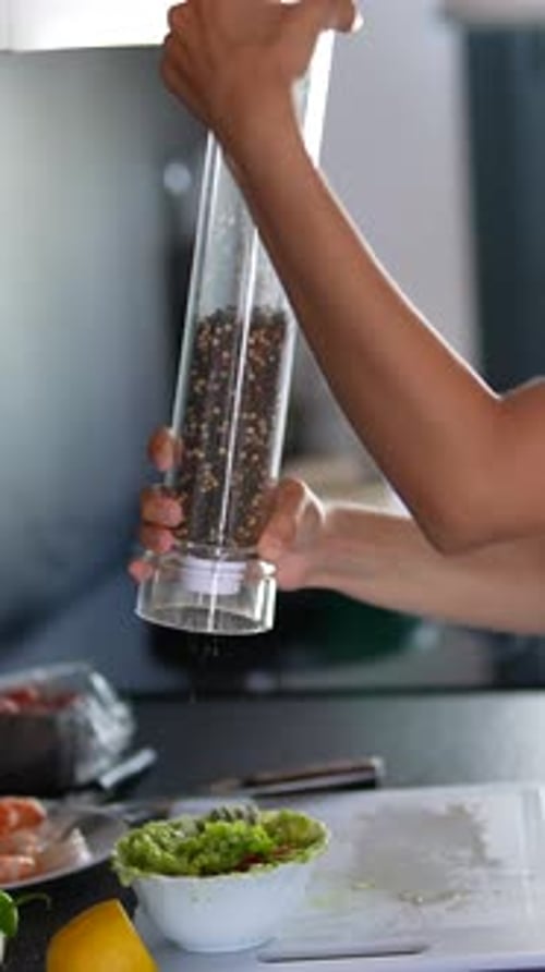 An Image Capturing a Closeup of a Hand Using a Tall Pepper Grinder in a Stylish Kitchen Setting