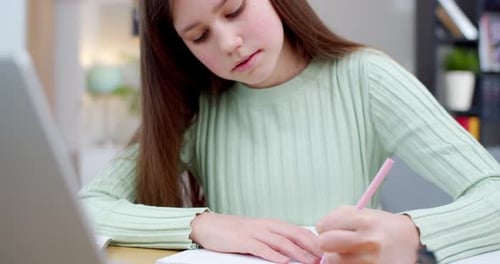 Close Up of Beautiful Caucasian Teen Girl Sitting at Laptop Writing Exercise in Copybook and Having