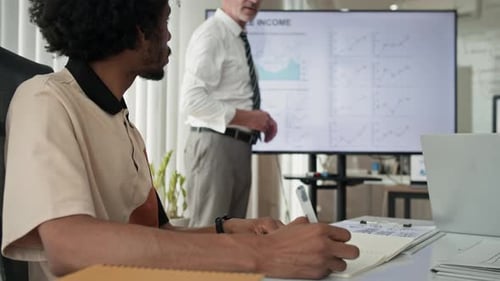 Employee Making Notes when Listening to Financial Manager Presentation at Office