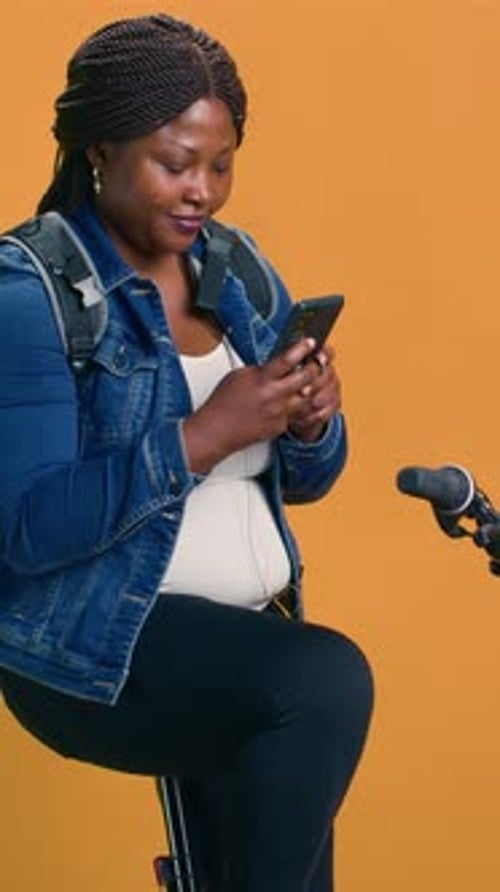 Woman Sits on Stool Looking at Phone in Studio