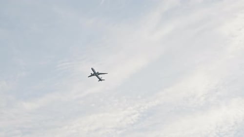 Distant airplane departing and flying past in morning light and blue sky