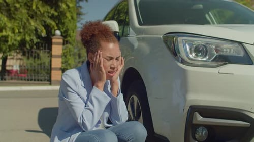 Distraught Woman Inspects Damage to Car Bumper