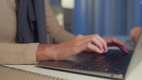 Hands Typing on Laptop Keyboard in Dim Light