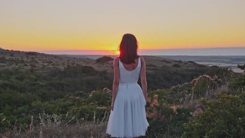 Wunderschöne junge Frau in Zeitlupe in einem weißen Kleid vor dem Hintergrund eines herrlichen Sommers