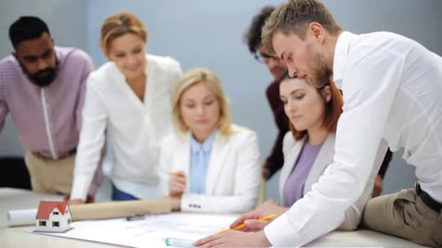 Multiethnic business team discusses house project blueprint at office meeting