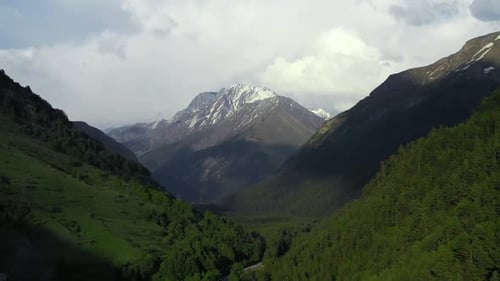 Valley with a Mountain in the Background and a River Running Through It with Snow on the Top of the