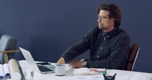 4k-Videomaterial eines gutaussehenden jungen männlichen Architekten, der Kaffee trinkt, während er in einem modernen Büro arbeitet