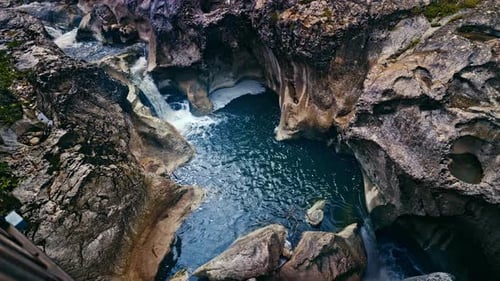 A captivating view of a natural rock formation with water rushing through it, creating deep pools an