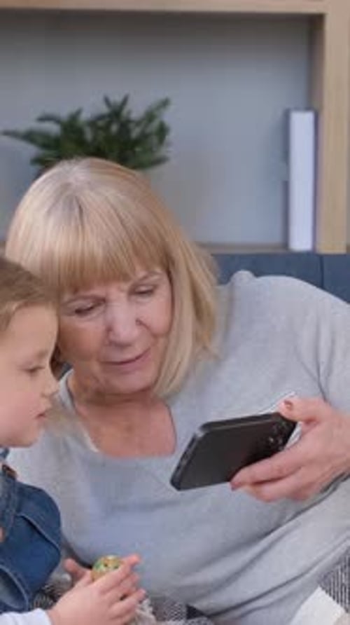 Grandmother and Child Watching Phone Together Indoors