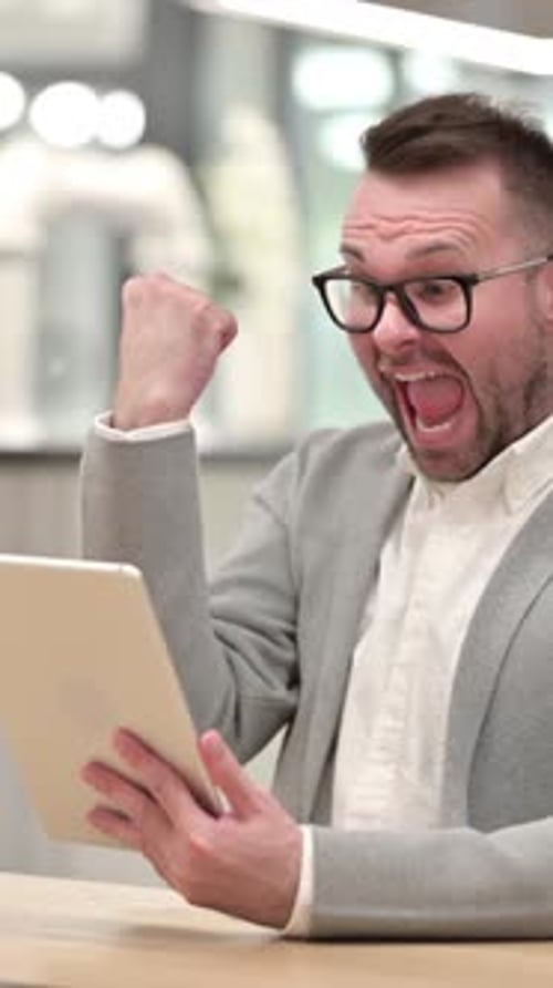 Man Celebrates Success While Using Tablet Device