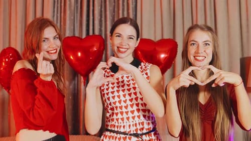 Cheerful Young Women Displaying Affection in Red
