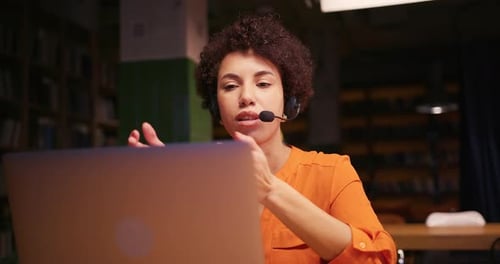 Woman With Headset Talking and Gesturing at Laptop