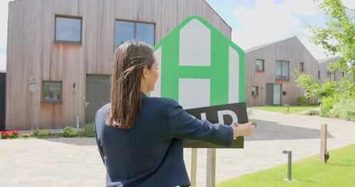 Real Estate Agent putting Sold Sign on Real Estate Sign, Sold Property