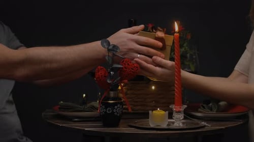 Couple Exchanging Romantic Gift at Candlelit Table