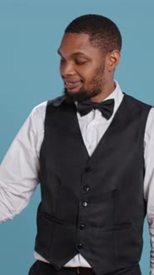 Professional Man in Bowtie Pointing Sideways on Blue Background