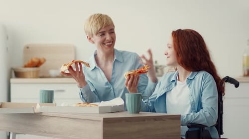 Two Women Enjoy Pizza Together at Home