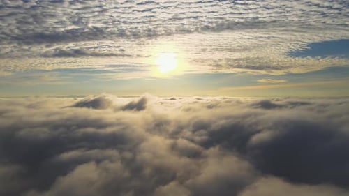 Aerial View of Vibrant Yellow Sunrise Over White Dense Clouds with Blue Sky Overhead