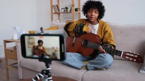 Young Woman Playing Guitar for Online Tutorial