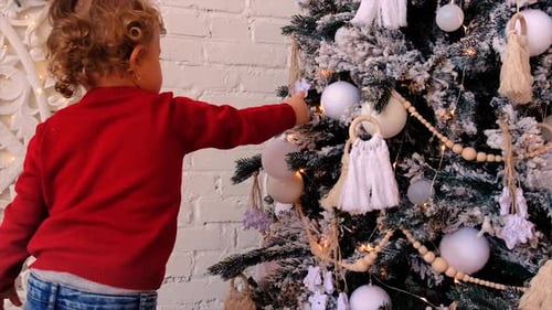 Toddler Decorating Christmas Tree with Ornaments at Home