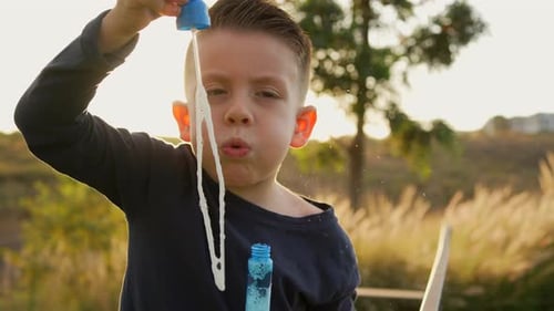 Boy Blowing Bubbles in Golden Sunset Light