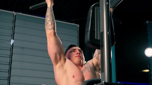Close Up in the Gym Young Handsome Guy with Tattoos is Doing Pullups on the Horizontal Bar Shaking