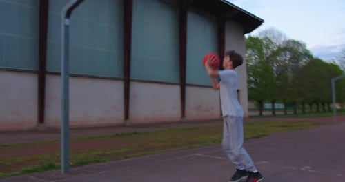 Video of a Boy Standing on a Basketball Court and Holding a Basketball Cinematic Shot of Teenager