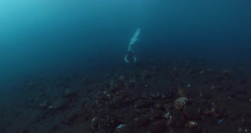 Deep Ocean Underwater and Woman Freediver Swims Close to the Sea Bottom