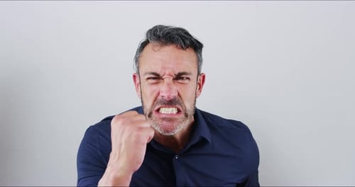 4k video footage of a mature businessman looking angry against a gray studio background