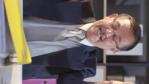 Smiling Man Opening Binder in the Office