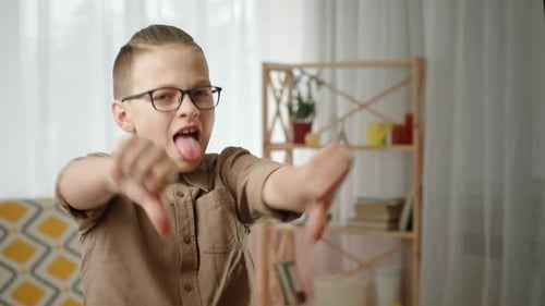 Boy Gives Two Thumbs Down with Tongue Out