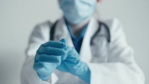 Doctor Puts On Blue Surgical Gloves in Hospital