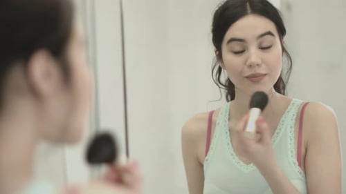 Young Woman Applying Makeup with Brush in Bathroom