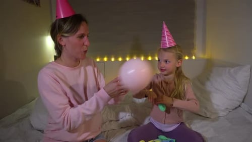Woman and Child Blowing up Birthday Balloons Indoors