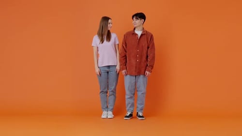 Cheerful Asian Man and European Woman Cross Arms in Studio