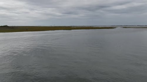 A low altitude, aerial view over the salt marshes in Hempstead, NY on a cloudy day. The drone camera