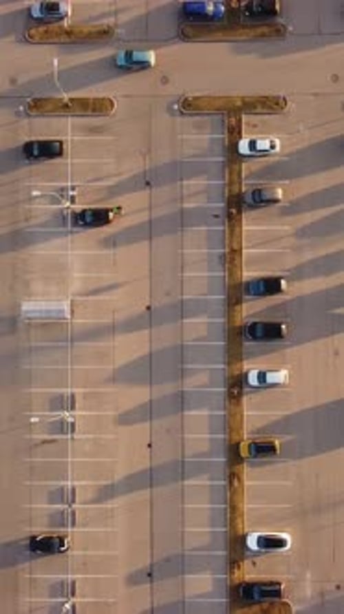 Vertical Top-Down View of Parking Rows with Few Cars at Sunset