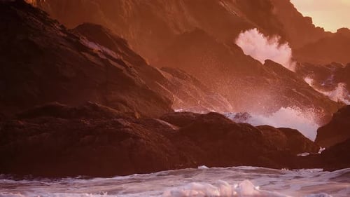 Ondas tempestuosas atingindo montanhas costeiras escarpadas durante o pôr do sol. Câmera lenta